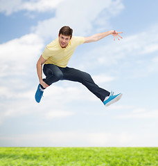 Image showing smiling young man jumping in air