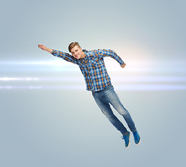 Image showing smiling young man jumping in air