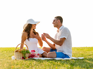 Image showing smiling couple with small red gift box on picnic