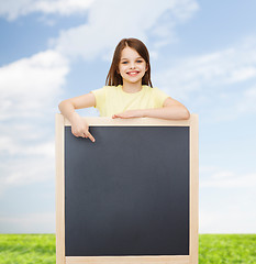 Image showing happy little girl pointing finger to blackboard