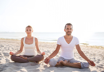 Image showing smiling couple making yoga exercises outdoors