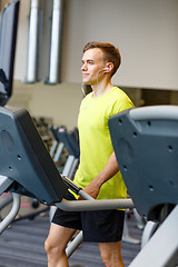 Image showing man with smartphone exercising on treadmill in gym