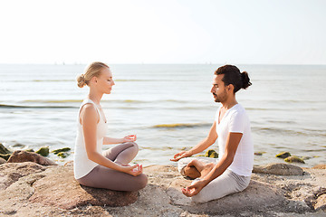 Image showing smiling couple making yoga exercises outdoors