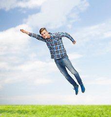 Image showing smiling young man jumping in air