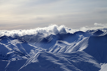 Image showing Evening snowy mountains in mist and sunlight clouds