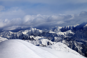 Image showing Off-piste snowy slope and mountains in cloud