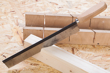 Image showing Hand saw cutting through a beam of wood