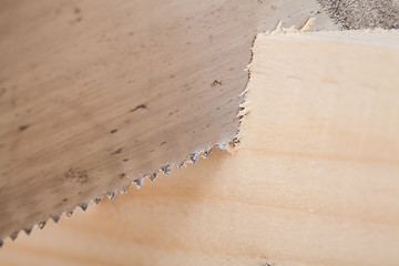 Image showing Hand saw cutting through a beam of wood