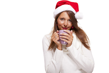 Image showing Cold young woman in a Santa hat sipping coffee tea