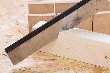 Image showing Hand saw cutting through a beam of wood