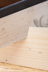 Image showing Hand saw cutting through a beam of wood