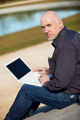 Image showing Man sitting on a bench using a laptop