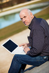 Image showing Man sitting on a bench using a laptop