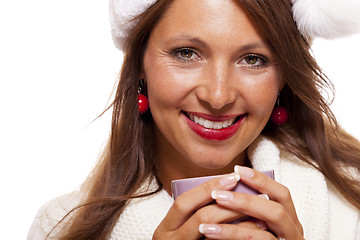 Image showing Cold young woman in a Santa hat sipping coffee tea