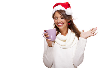 Image showing Cold young woman in a Santa hat sipping coffee tea