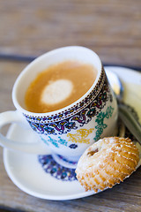 Image showing Cup of freshly brewed tea and a cookie