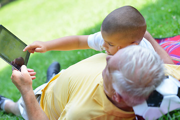 Image showing grandfather and child in park using tablet