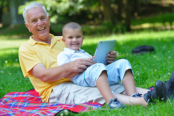 Image showing grandfather and child in park using tablet