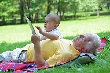 Image showing grandfather and child in park using tablet