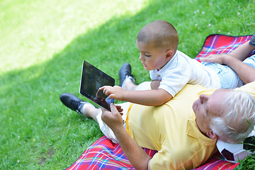 Image showing grandfather and child in park using tablet