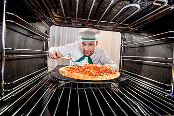 Image showing Chef cooking pizza in the oven.