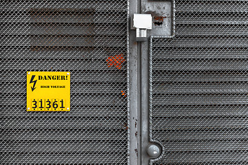 Image showing Grey fence with yellow warning sign