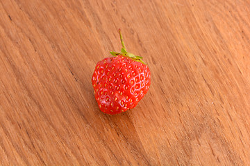 Image showing close up of small strawberry on wood