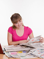 Image showing Girl looking for the right ad in newspaper