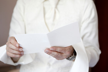 Image showing Groom is reading a white greeting card