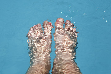 Image showing Splashing female feet in a swimming pool