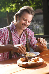 Image showing Attractive man eats traditional cheese with pretzel in a Bavaria