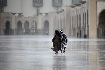 Image showing Two Moroccans run through the rain