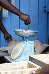 Image showing African carpenter weighs nails on a scale 