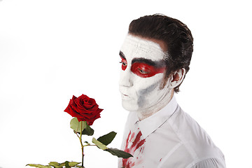 Image showing Man with white mascara and bloody shirt holds red rose