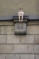 Image showing Figure of a girl sitting on the house wall