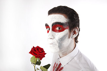 Image showing Man with white mascara and bloody shirt holds red rose