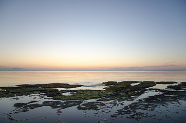 Image showing Sunset at a flat rock coast