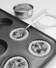 Image showing Using teaspoon to fill pastry cases with mincemeat