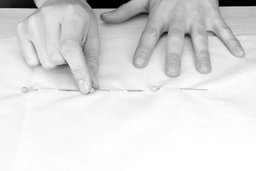Image showing Closeup of large upholstery pins being pinned into plain fabric