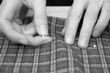 Image showing Closeup of two hands pinning plaid fabric