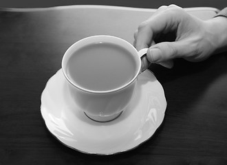 Image showing Woman picking up a cup of tea from a table