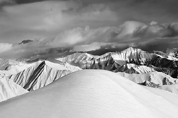 Image showing Black and white  off-piste snowy slope and cloudy mountains