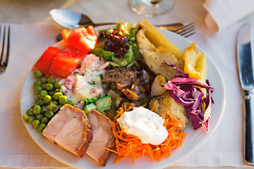 Image showing Meat, fish and various vegetable garnish on a plate.