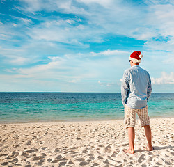 Image showing Man in santa hat on the tropical beach