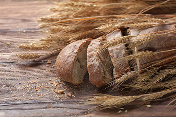 Image showing Bread and wheat on wooden table, shallow DOF