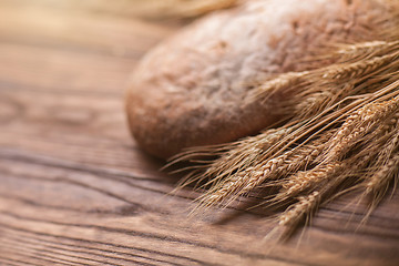 Image showing wheat and bread on wooden table, shallow DOF