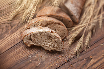 Image showing Bread and wheat on wooden table, shallow DOF