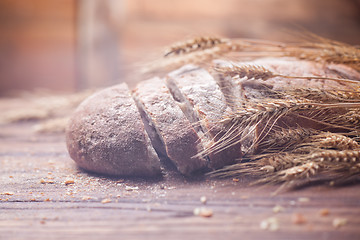 Image showing Bread and wheat on wooden table, shallow DOF