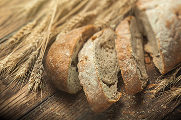 Image showing Bread and wheat on wooden table, shallow DOF