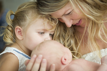 Image showing Young Mother Holds Newborn Baby Girl as Young Sister Looks